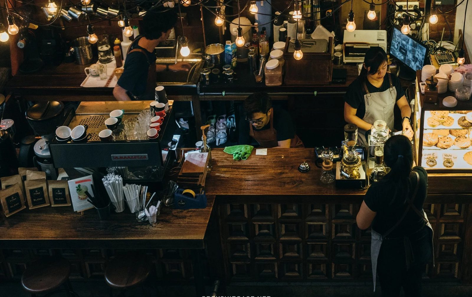 Pison coffee bar — late night, hanging Edison bulbs, baristas at the counter